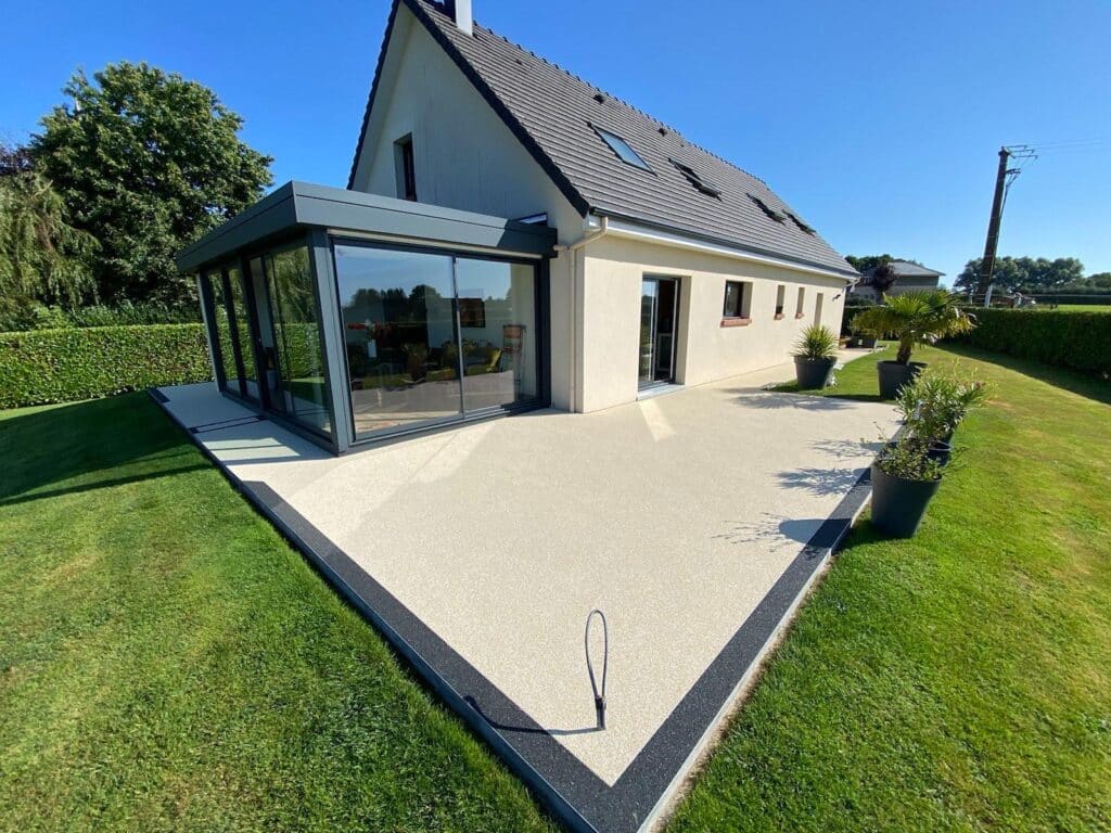Revêtement de sol en moquette de pierre beige avec bordure noire autour d'une maison à Rouen